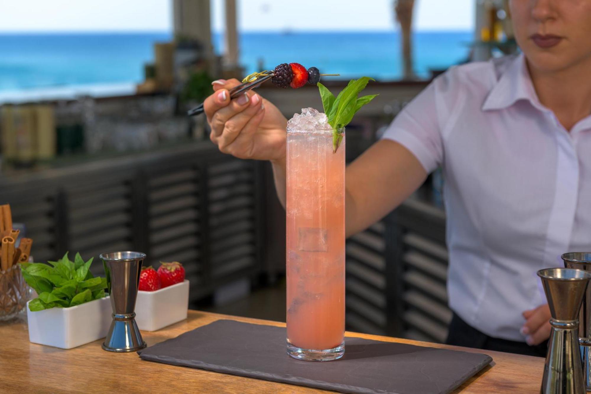Rodos Palladium Leisure & Wellness Mourátagas Exterior photo A bartender garnishes a cocktail with a fruit skewer.